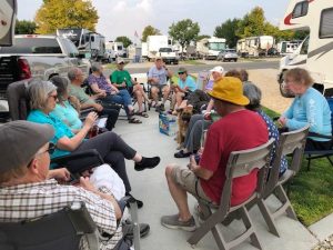 group of people sitting in chairs outside at rv campsite