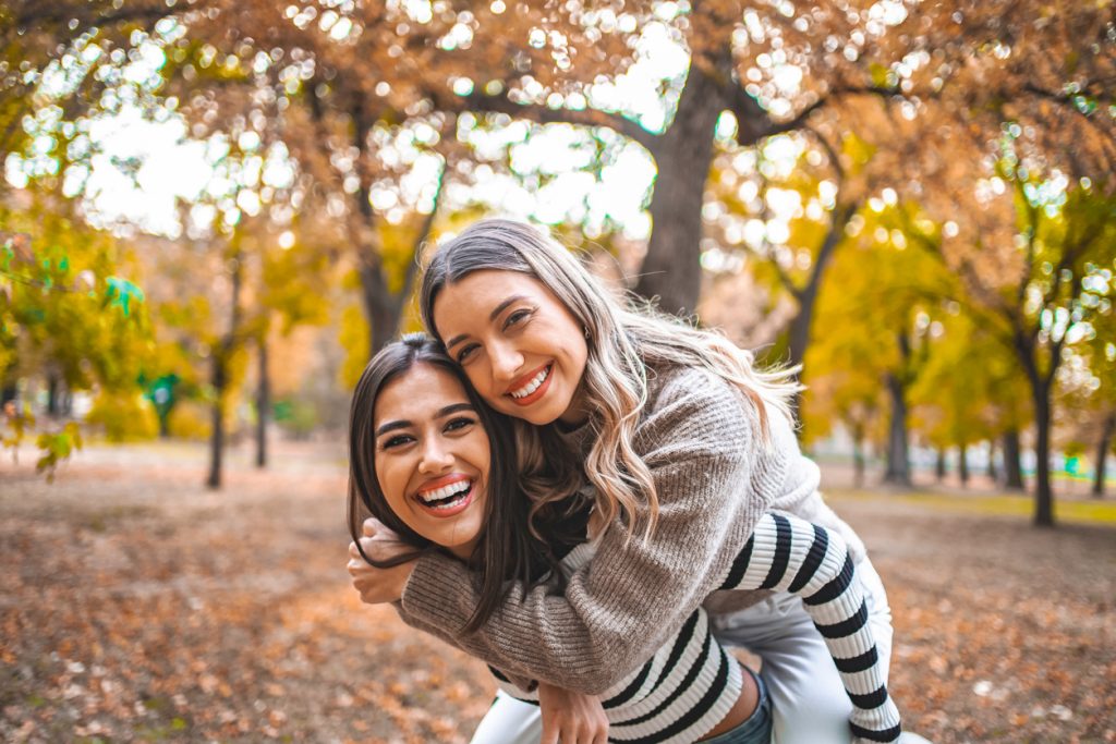 Two happy bestfriends having fun in the park in autumn